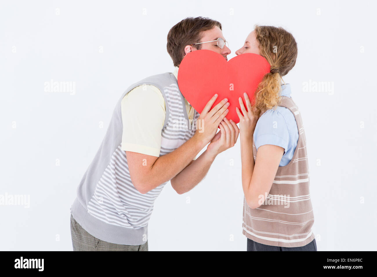Geeky hipster couple kissing behind heart card Stock Photo - Alamy