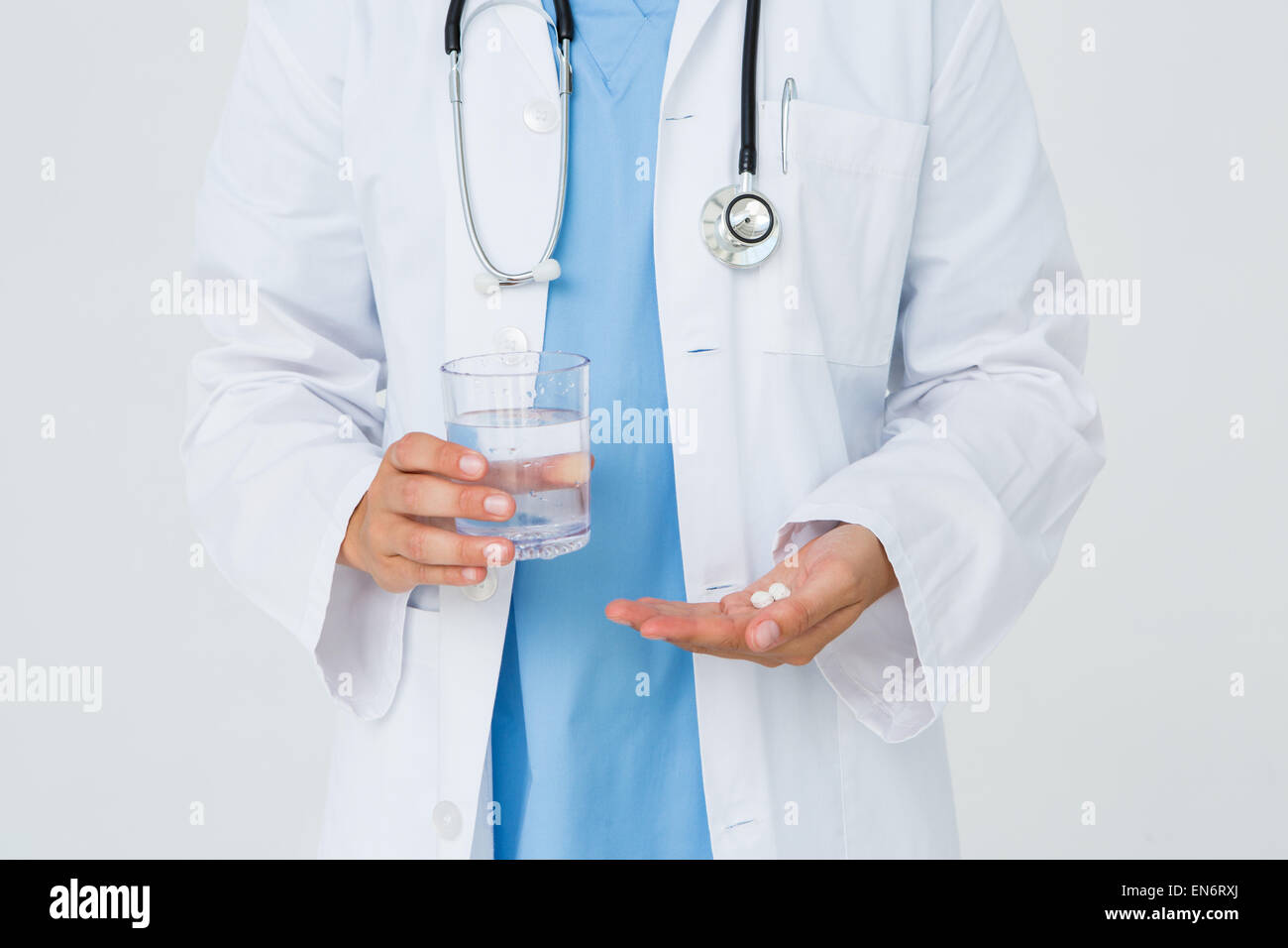 Doctor holding glass of water and pills Stock Photo