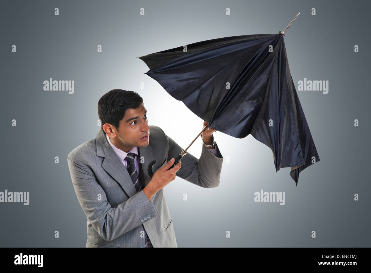 Businessman trying to open umbrella Stock Photo Alamy