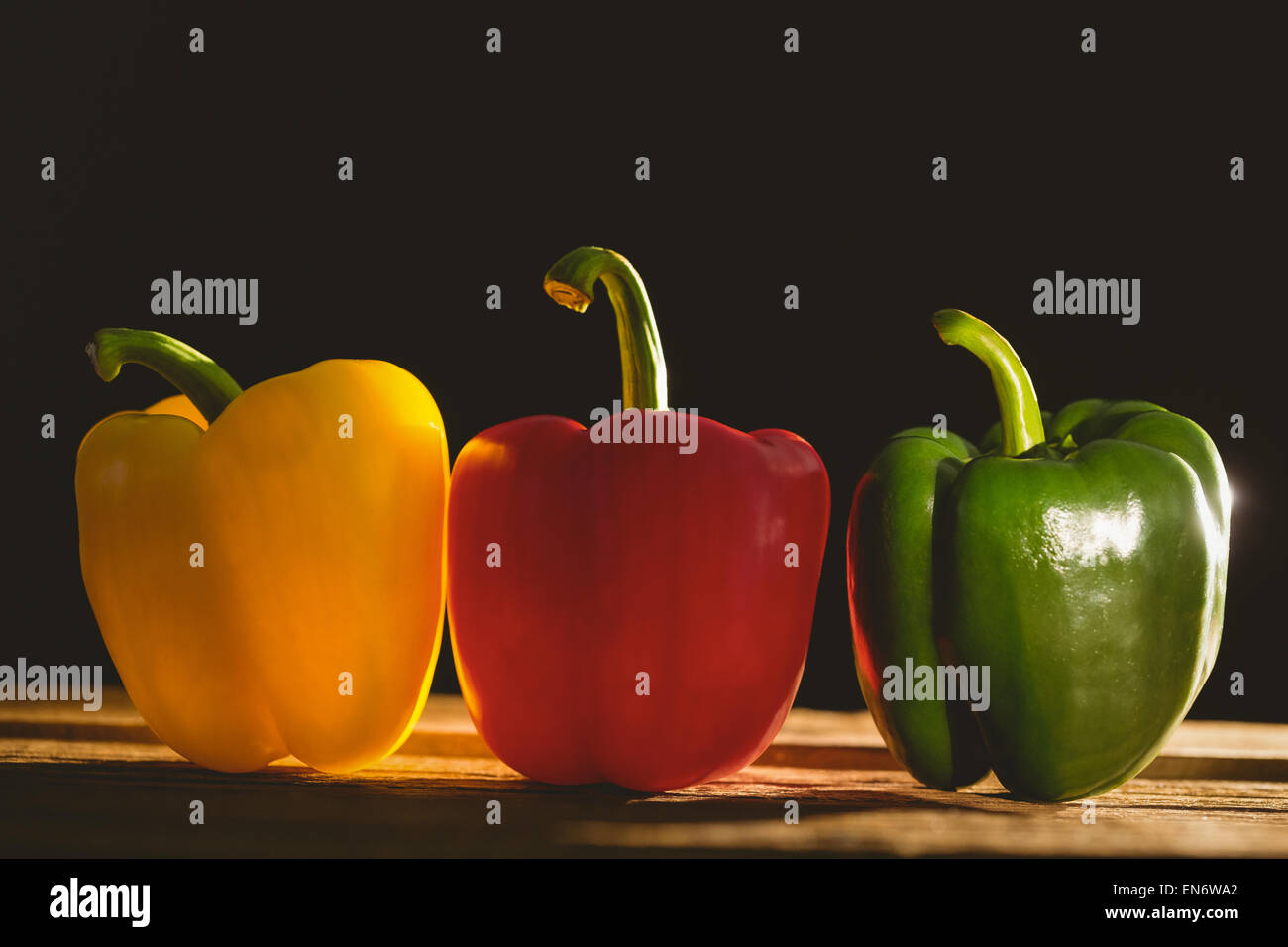 Three peppers on chopping board Stock Photo - Alamy