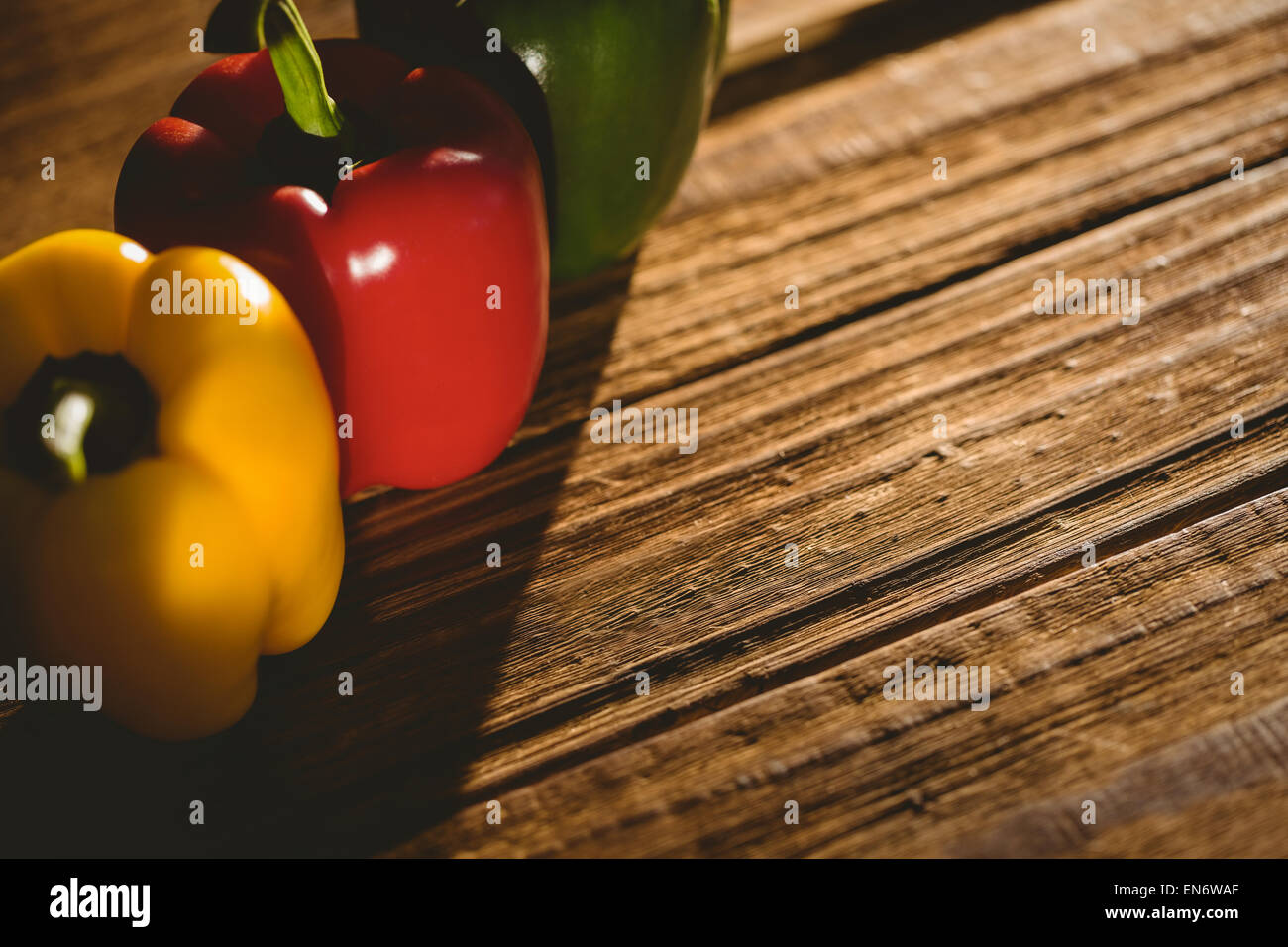 Three peppers on chopping board Stock Photo - Alamy