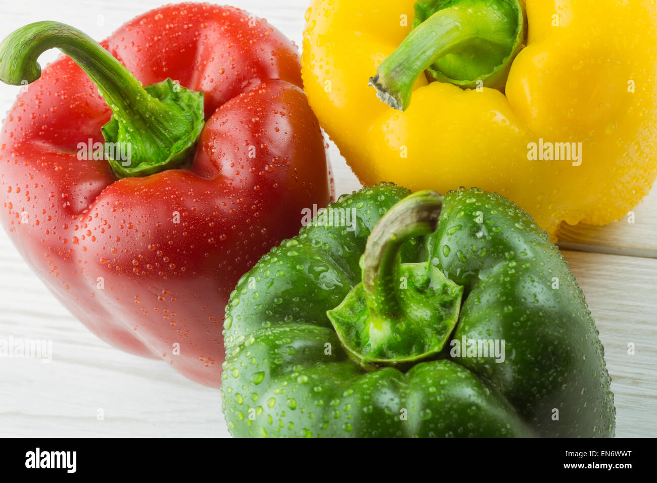 Three peppers on chopping board Stock Photo - Alamy