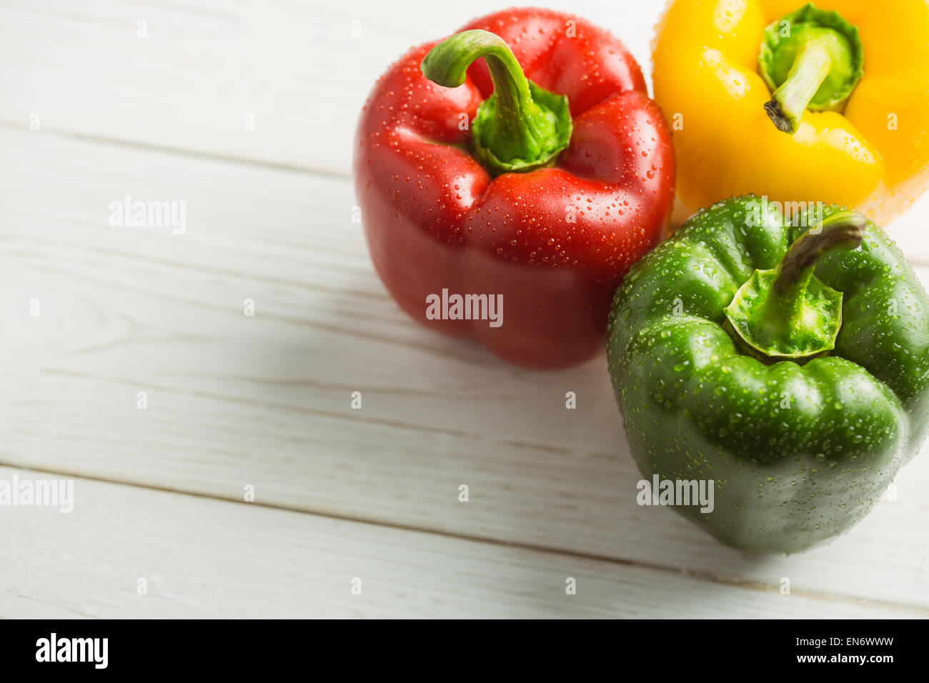 Three peppers on chopping board Stock Photo - Alamy