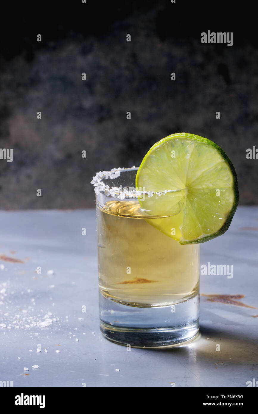 Short of tequila anejo with lime and salt over gray metal table Stock Photo