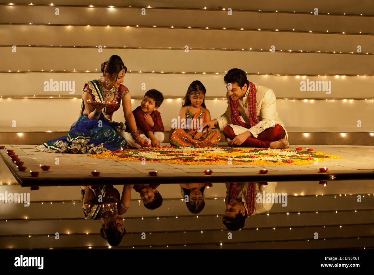 Family arranging diyas on rangoli Stock Photo - Alamy