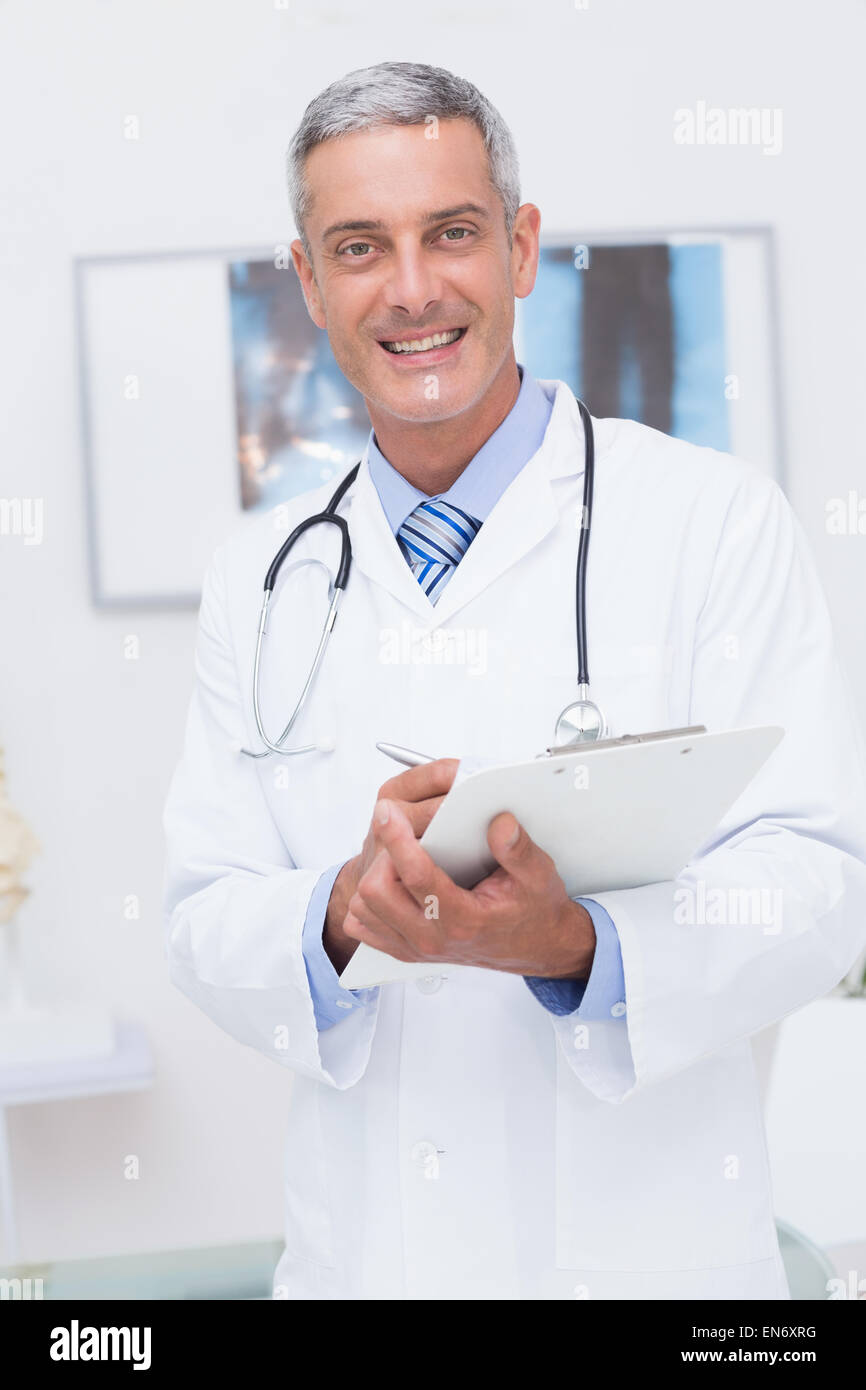 Happy doctor holding clipboard and smiling at camera Stock Photo - Alamy