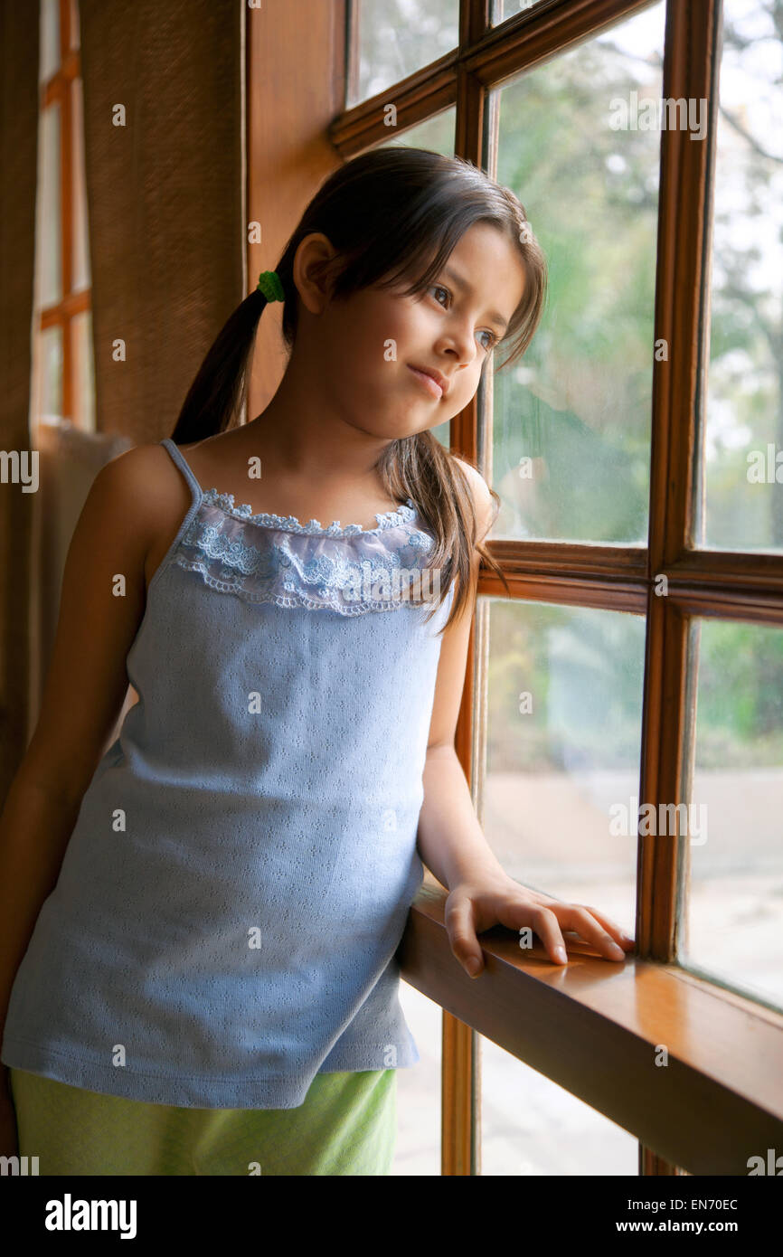 Little girl looking out of a window Stock Photo