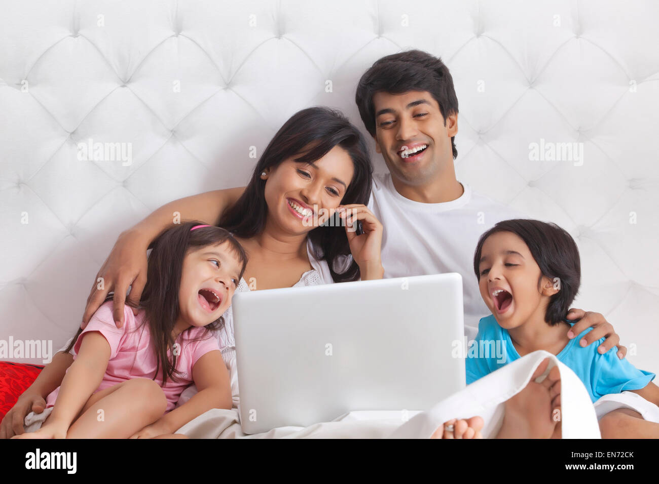 Family looking at laptop and laughing Stock Photo