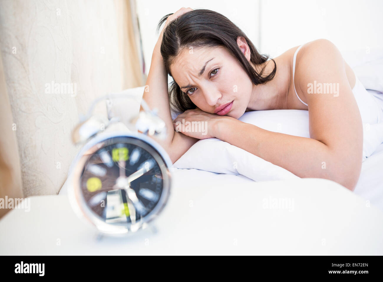 Pretty watching alarm clock on bed Stock Photo Alamy