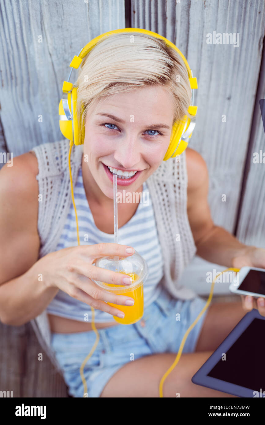 Pretty blonde woman listening music with her mobile phone and ...