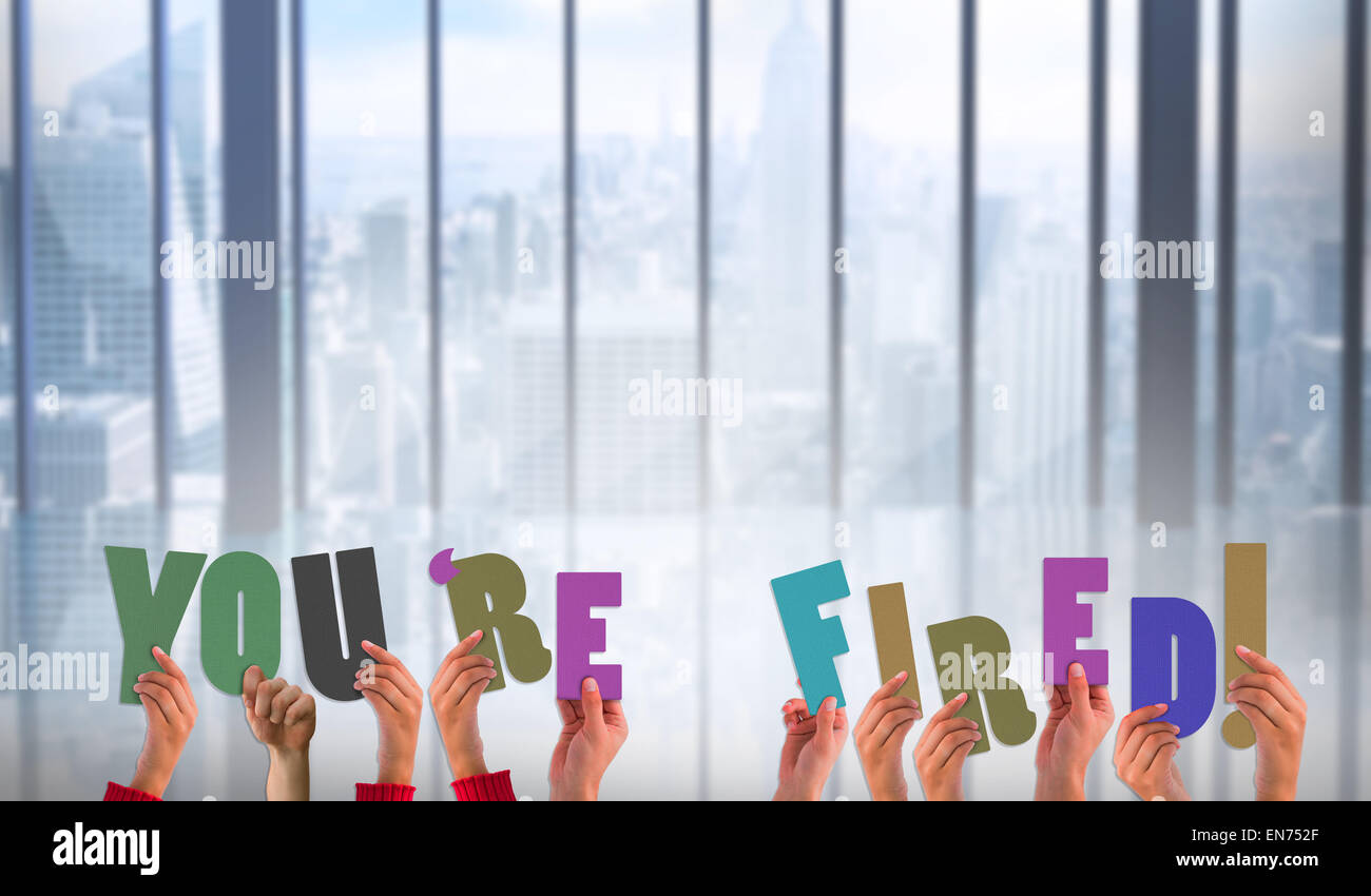 Composite image of hands holding up youre fired Stock Photo