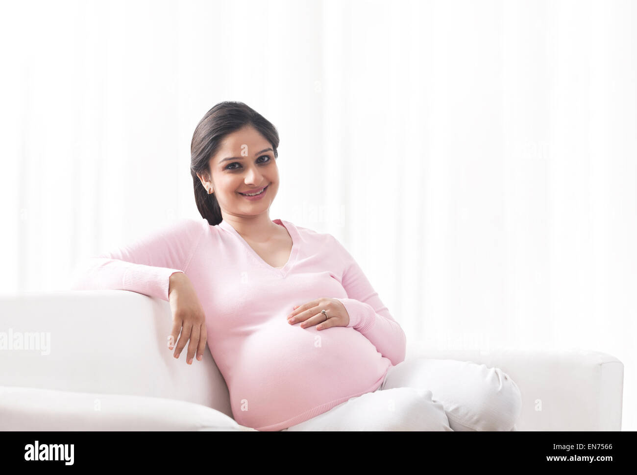 Portrait of a pregnant woman sitting on a couch Stock Photo