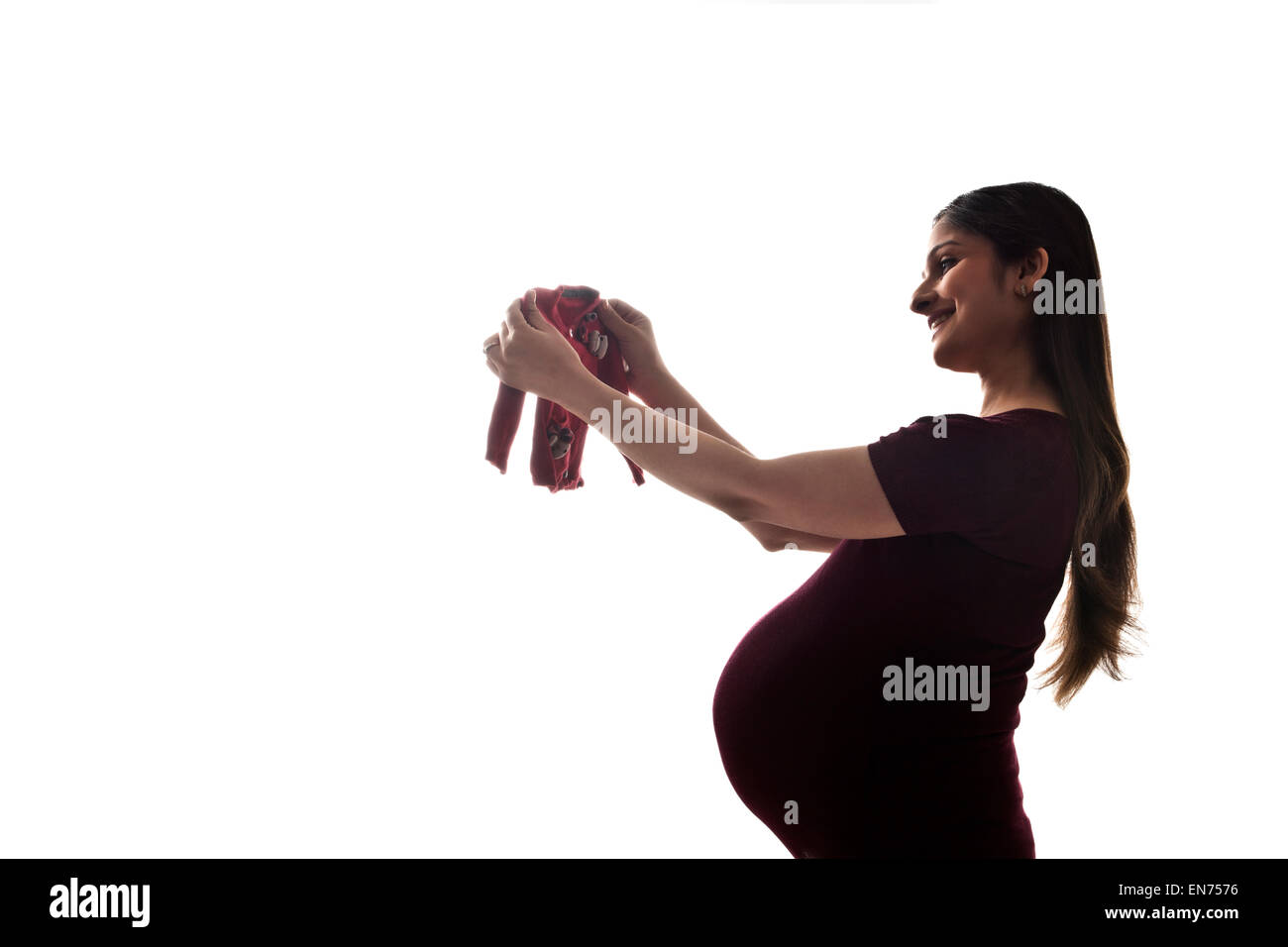 Pregnant woman holding baby clothing Stock Photo