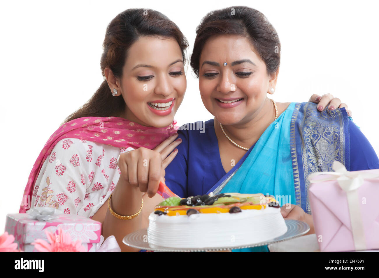 Woman cutting birthday cake while daughter looks on Stock Photo