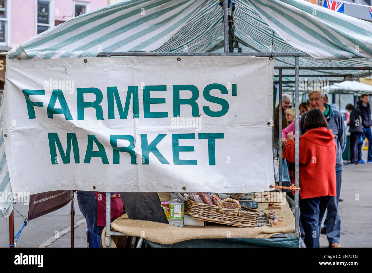 A Farmers' Market banner tied to a open air market stall in Cirecnester, Gloucestershire, UK. Shoppers are in the background. Stock Photo