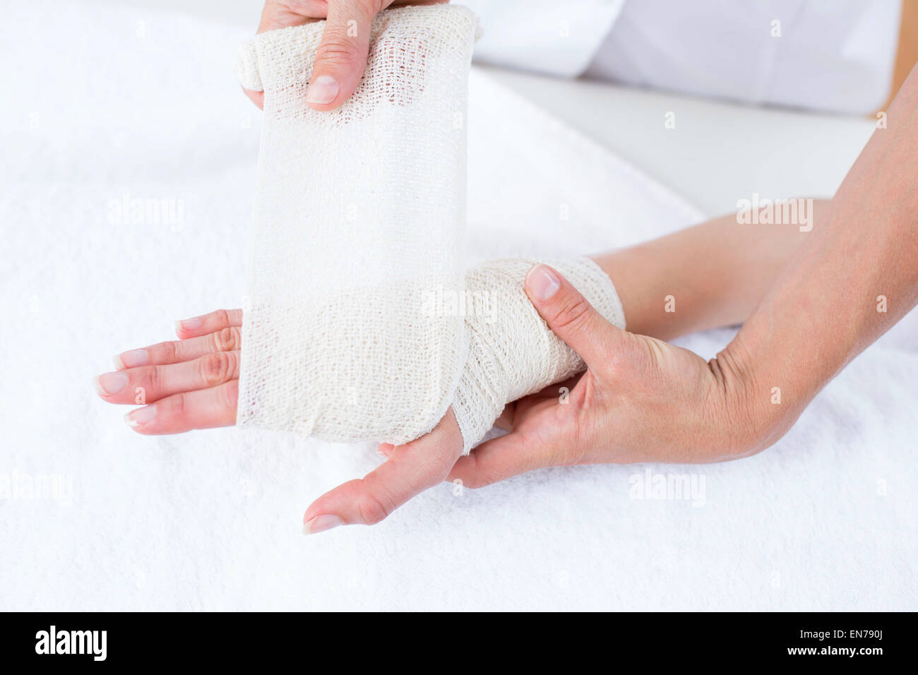 Doctor bandaging her patient wrist Stock Photo