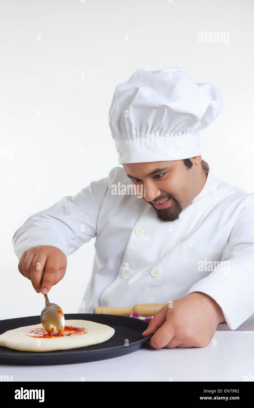 Chef applying topping on pizza dough Stock Photo