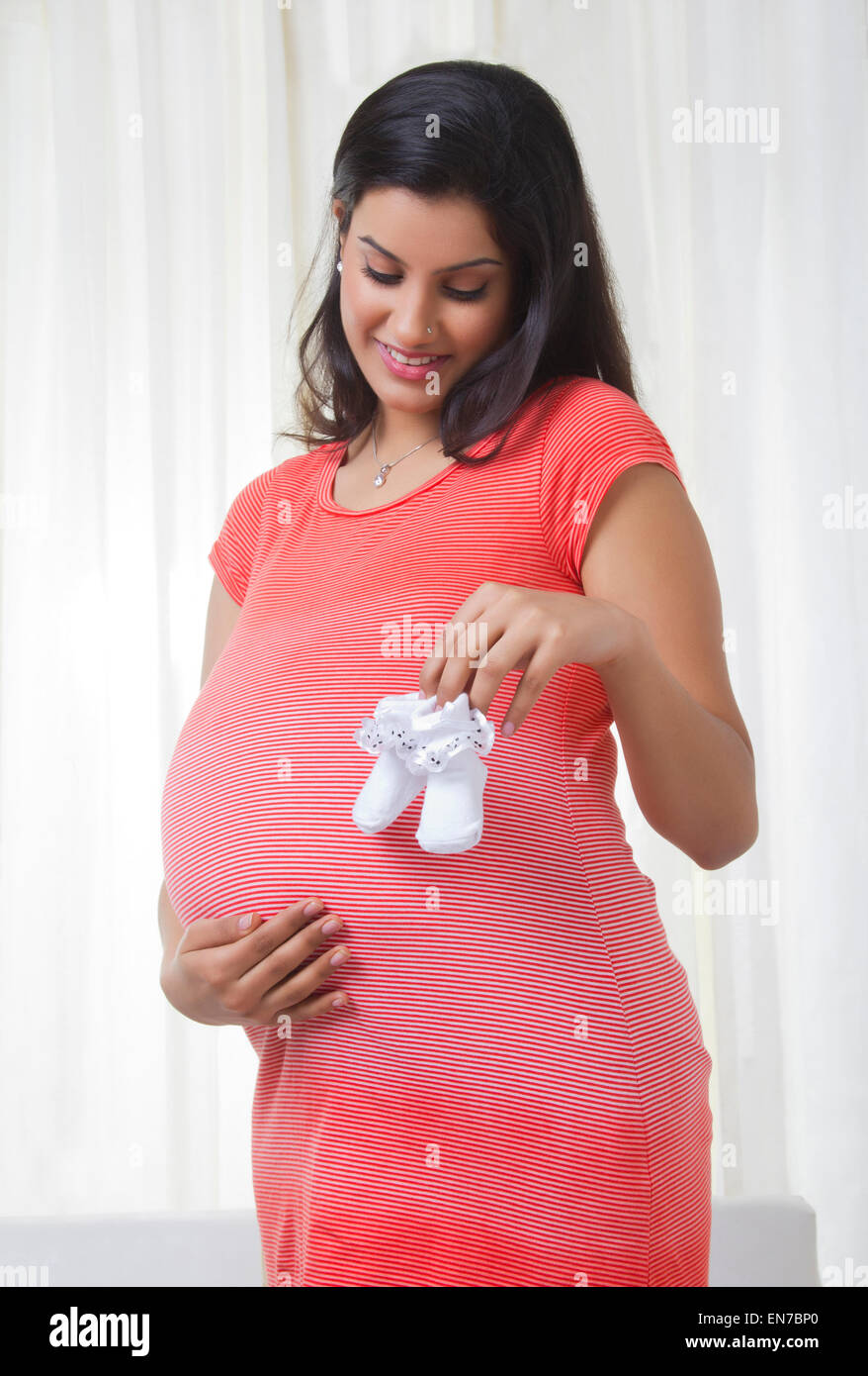 Pregnant mother holding baby shoes Stock Photo