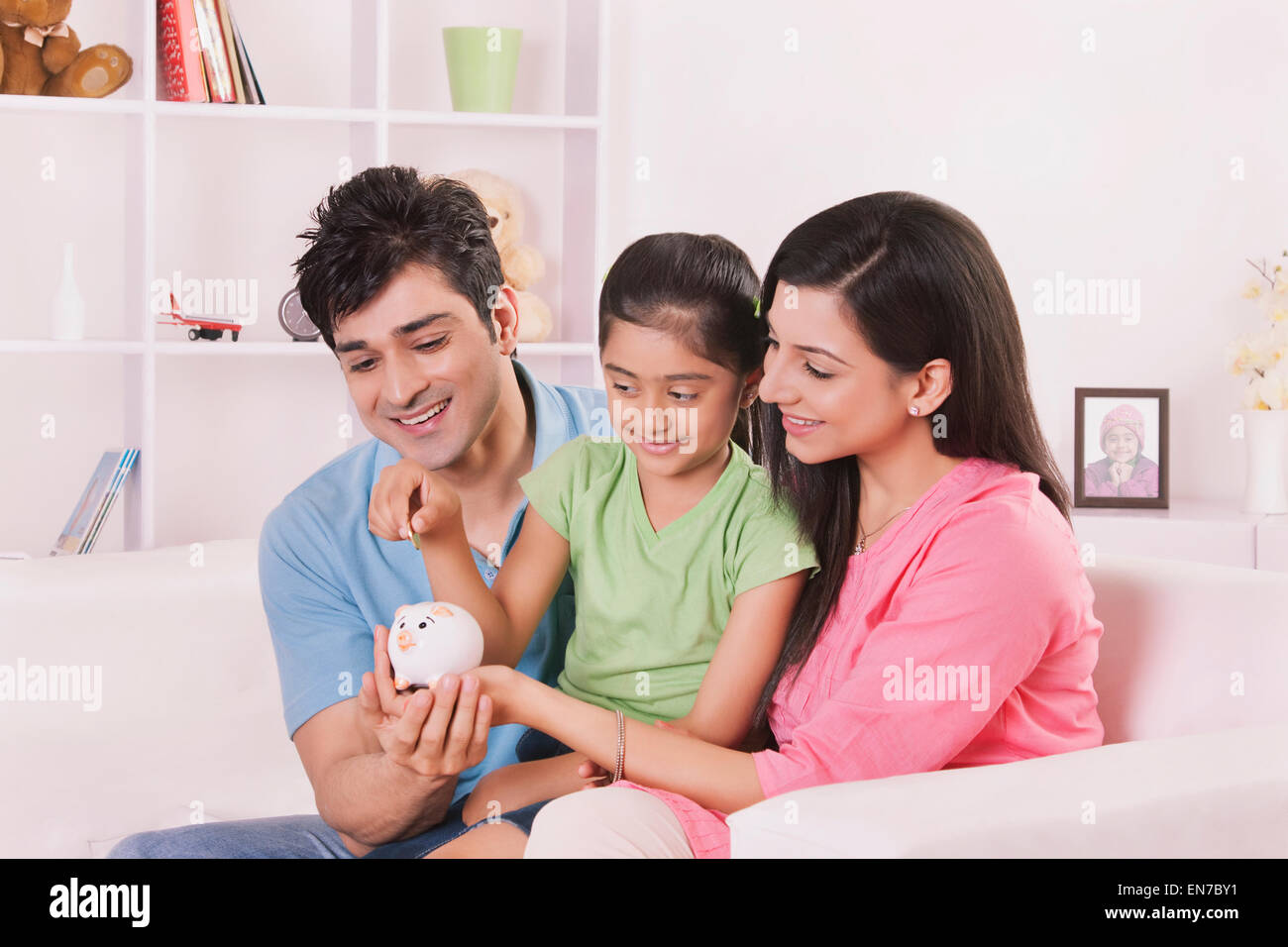 Girl putting coin in piggy bank Stock Photo - Alamy