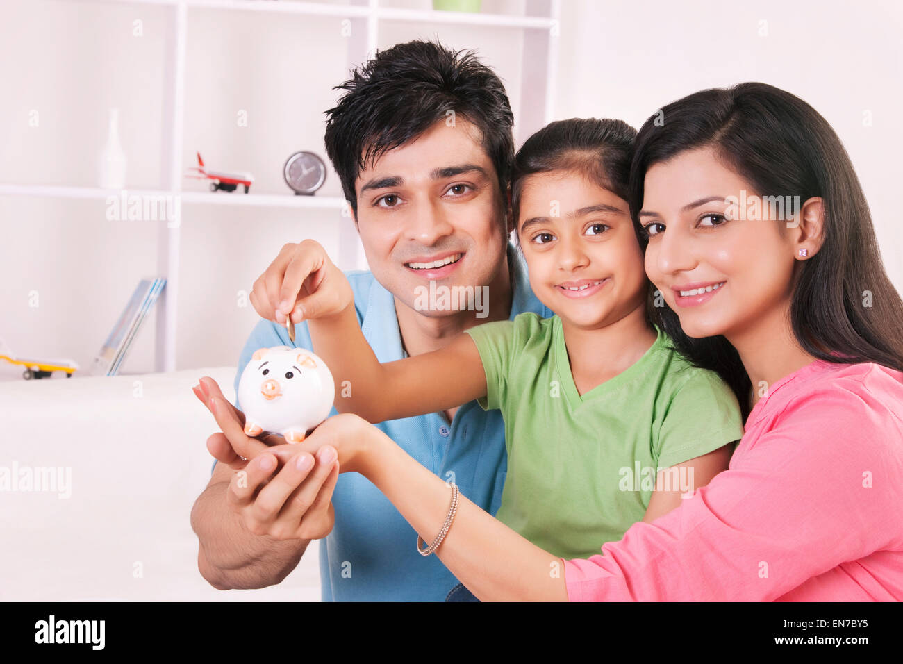 Portrait of girl putting coin in piggy bank Stock Photo - Alamy