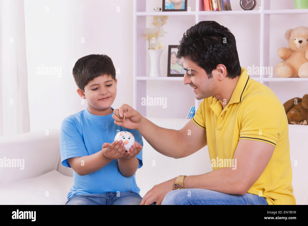Man putting coin into piggy bank Stock Photo - Alamy