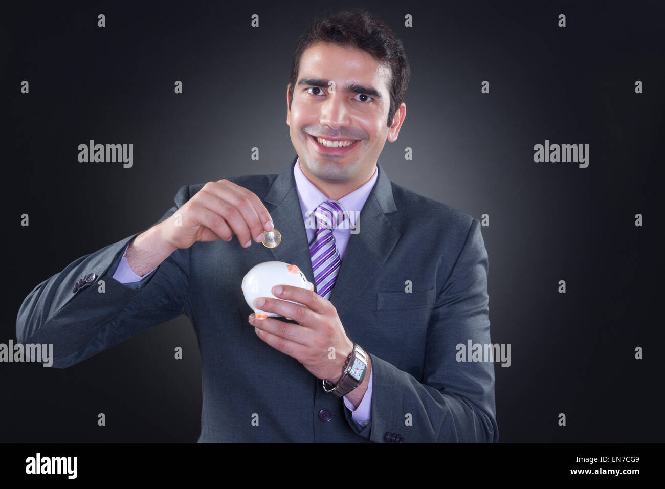 Portrait of businessman putting coin in piggy bank Stock Photo - Alamy