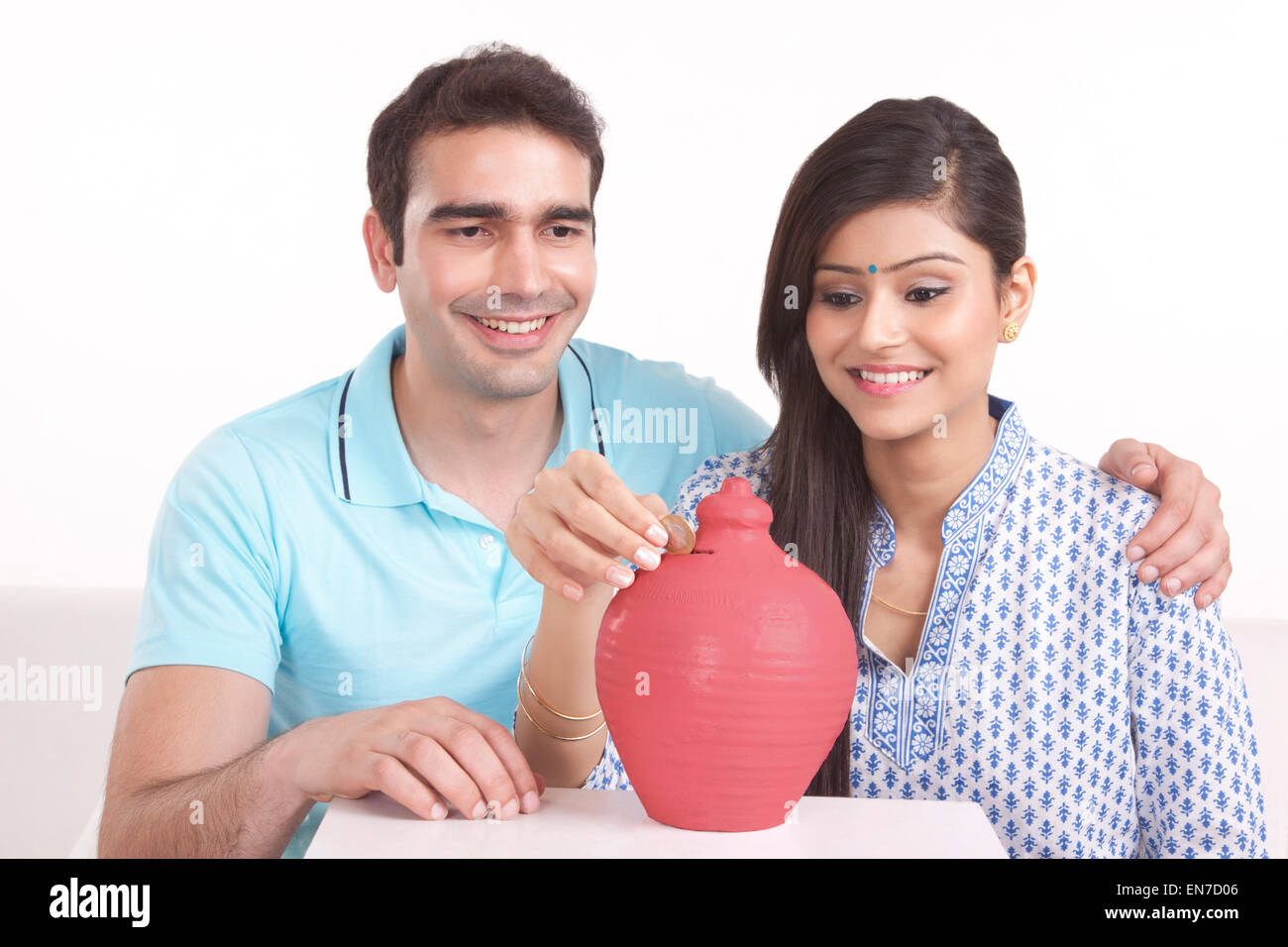 Couple putting money in piggy bank Stock Photo - Alamy