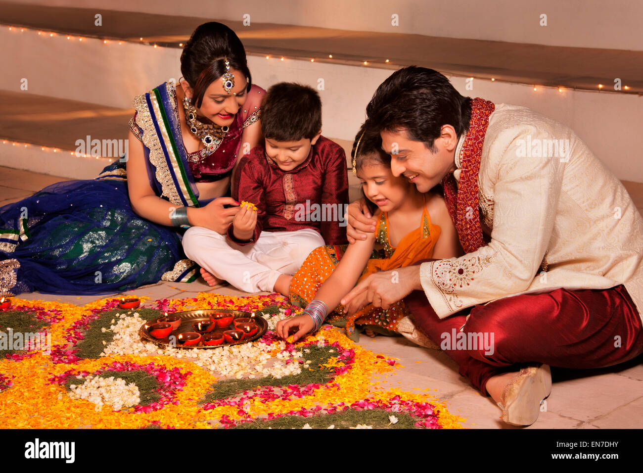 Family arranging diyas on rangoli Stock Photo - Alamy