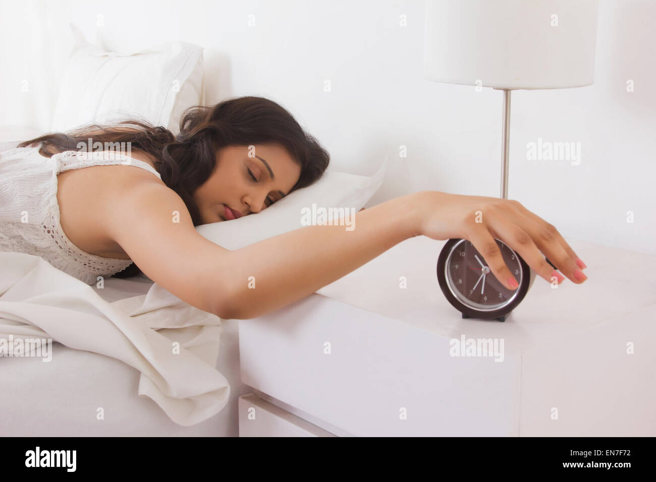 Woman with hand on bedside clock Stock Photo
