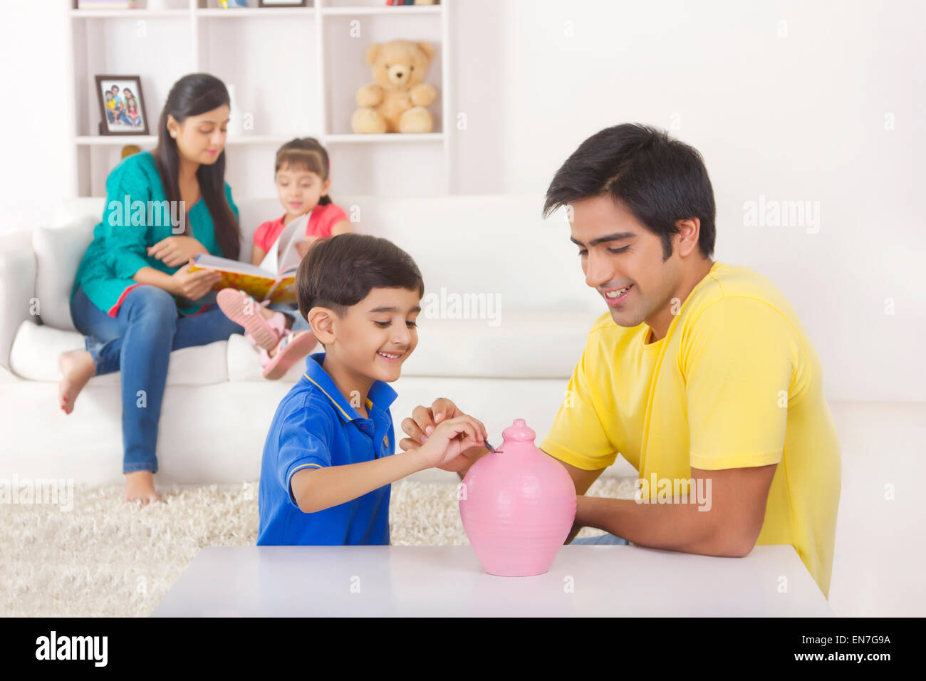 Boy putting coin in piggy bank Stock Photo - Alamy