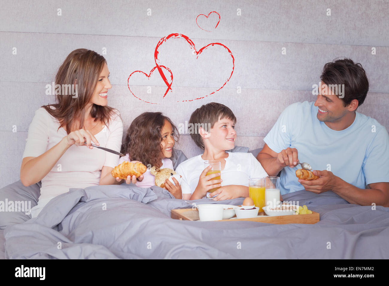 Composite image of family having breakfast in bed Stock Photo