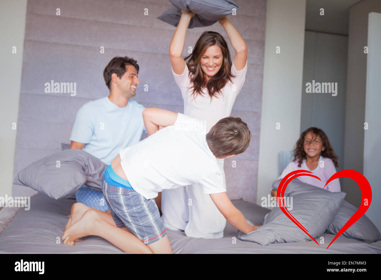 Composite image of family having a pillow fight on the bed Stock Photo