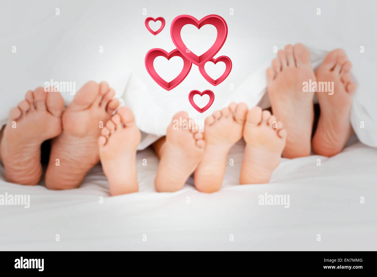 Composite image of  family on the bed at home with their feet showing Stock Photo
