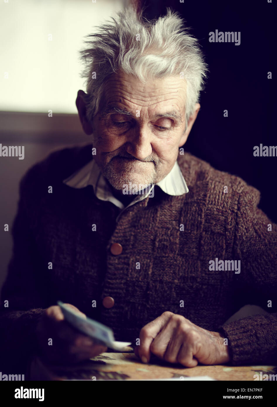 Old man in his 80s having just received his small pension, with a pensive expression on his face Stock Photo