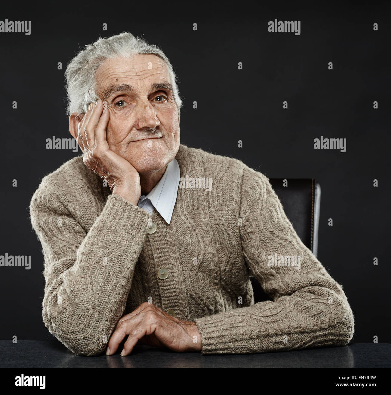 Happy 80 years old man sitting at the desk, studio shot Stock Photo Alamy