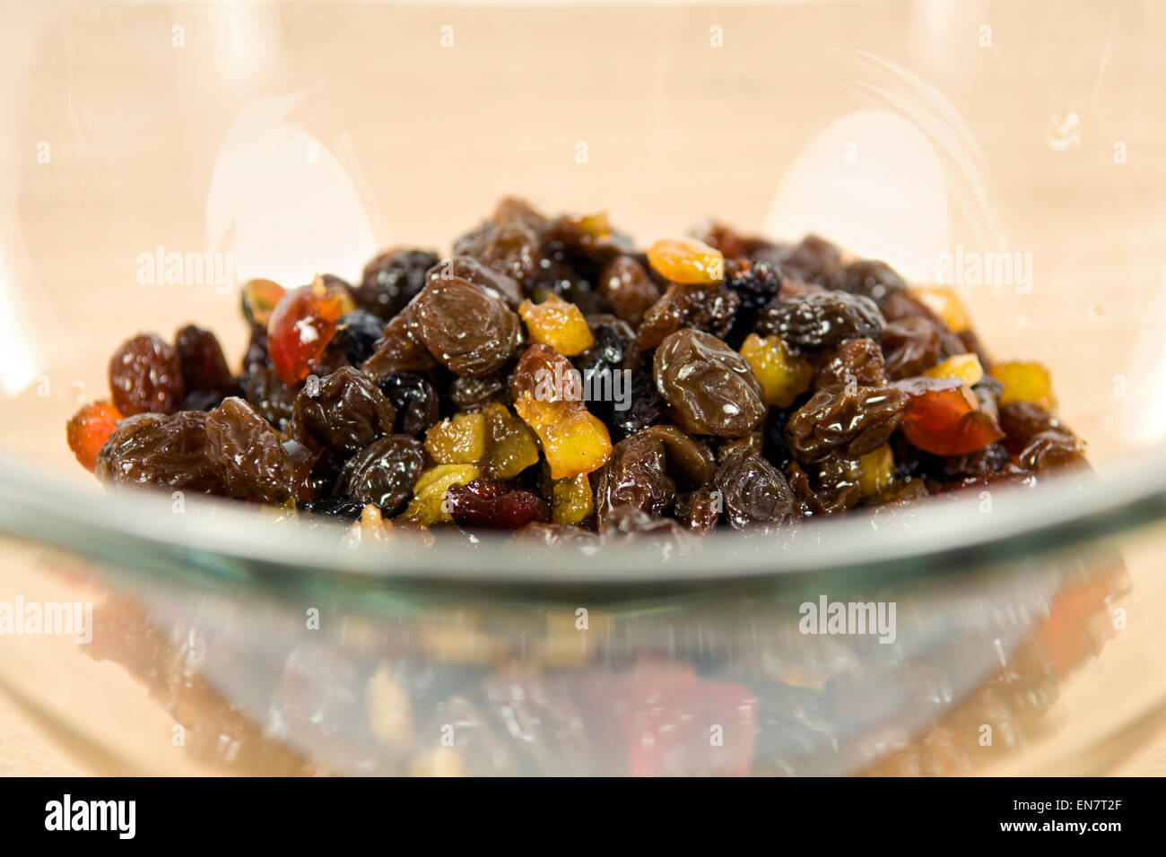 Dried fruit soaking in brandy in glass bowl in preparation for making a fruit cake Stock Photo