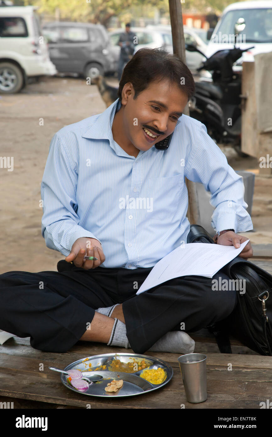 Salesman talking on a mobile phone and smiling holding papers Stock Photo