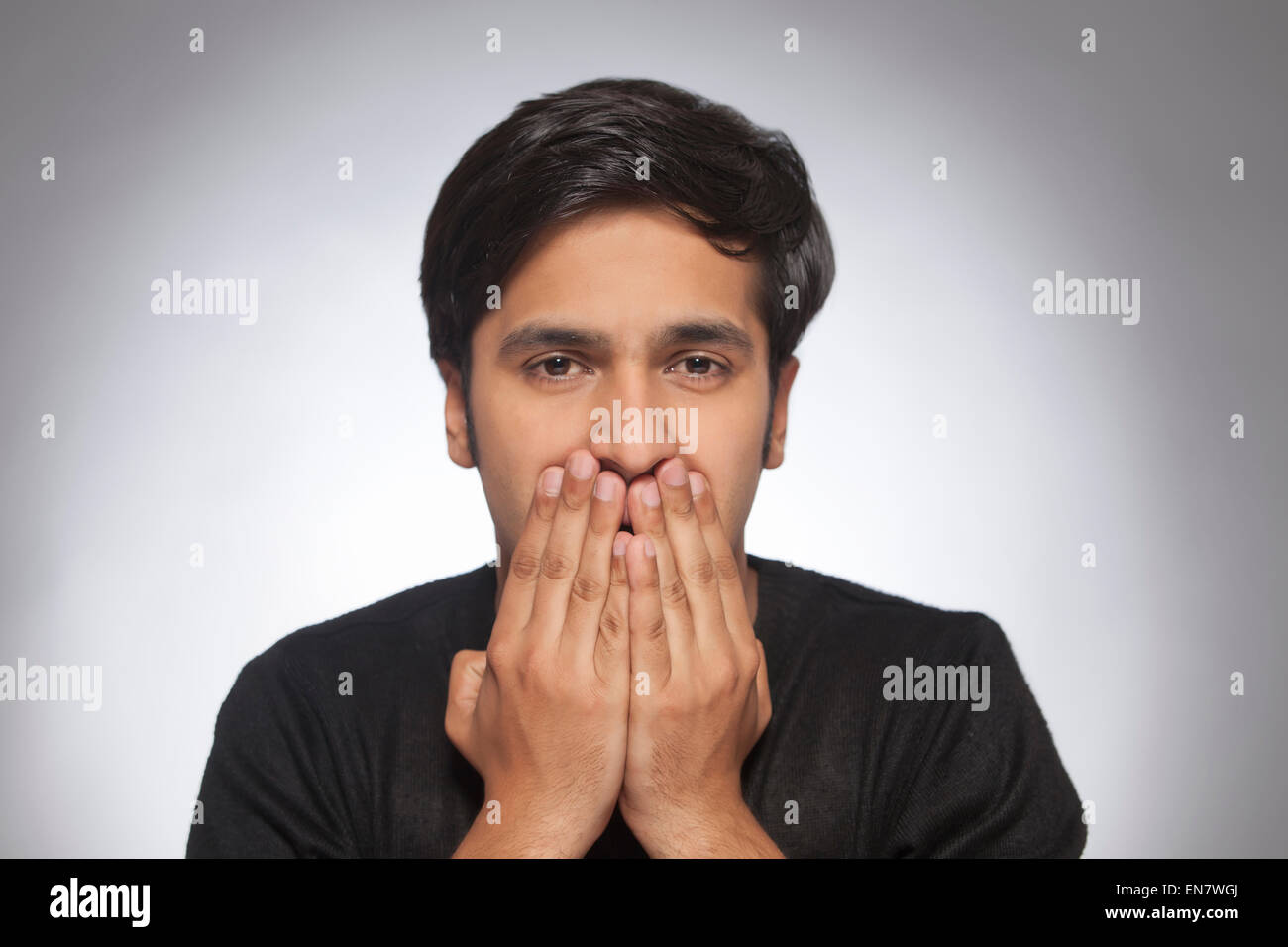 Portrait of a young man with hands over mouth Stock Photo Alamy