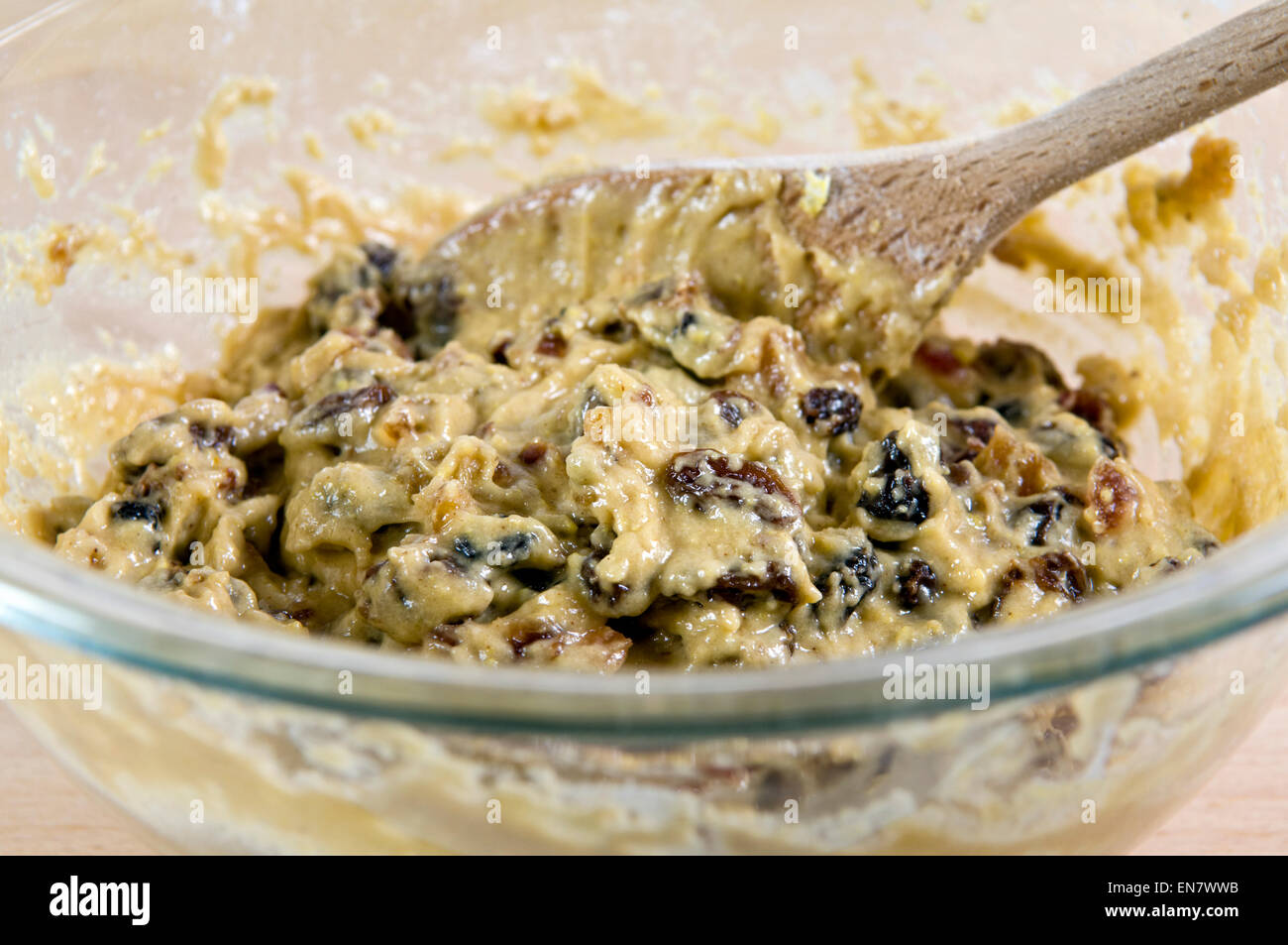 Fruit cake, or fruit loaf mixture in glass bowl with wooden spoon Stock Photo