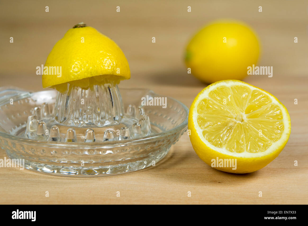 Lemons and lemon squeezer on chopping board Stock Photo