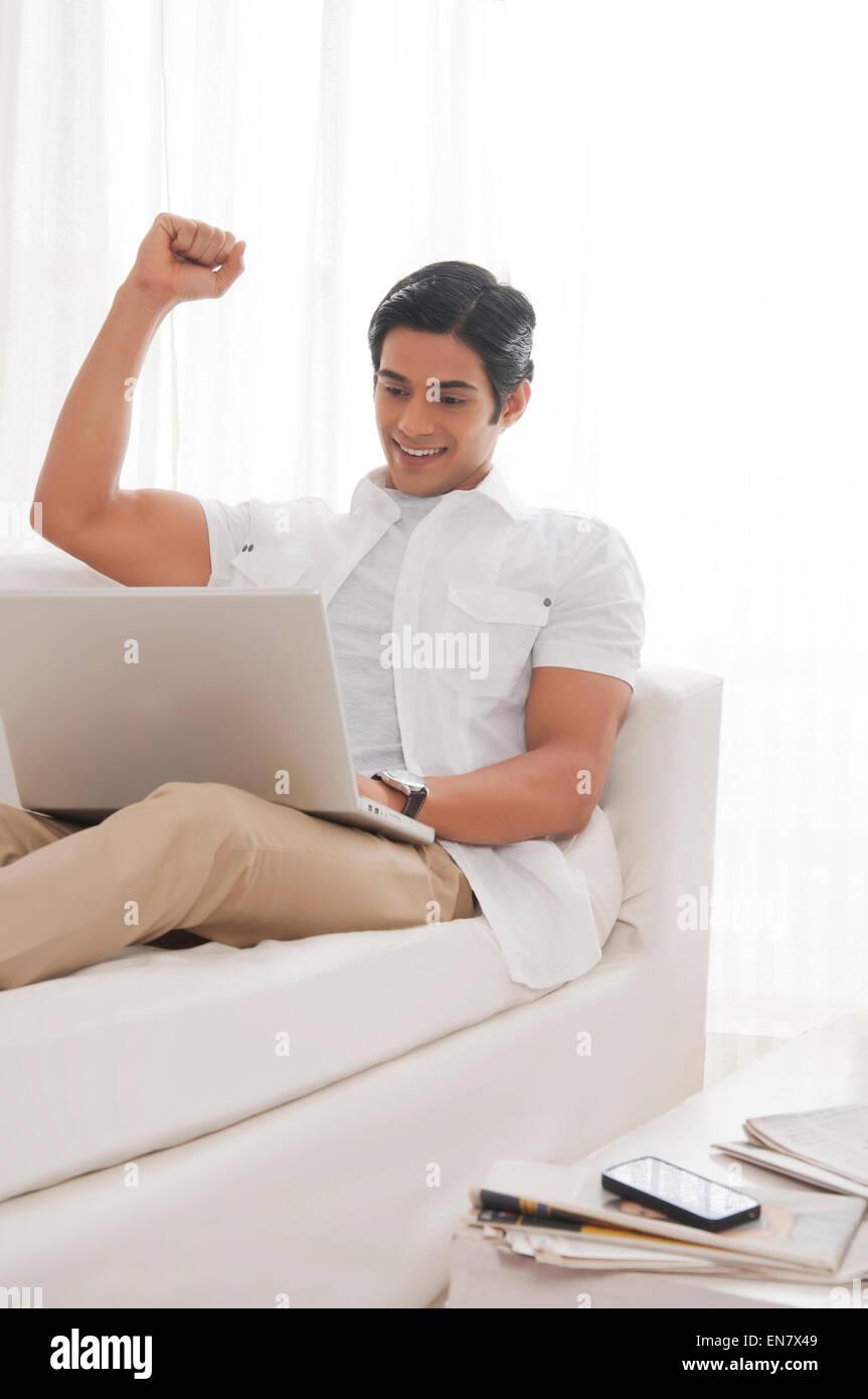 Young man with laptop rejoicing Stock Photo