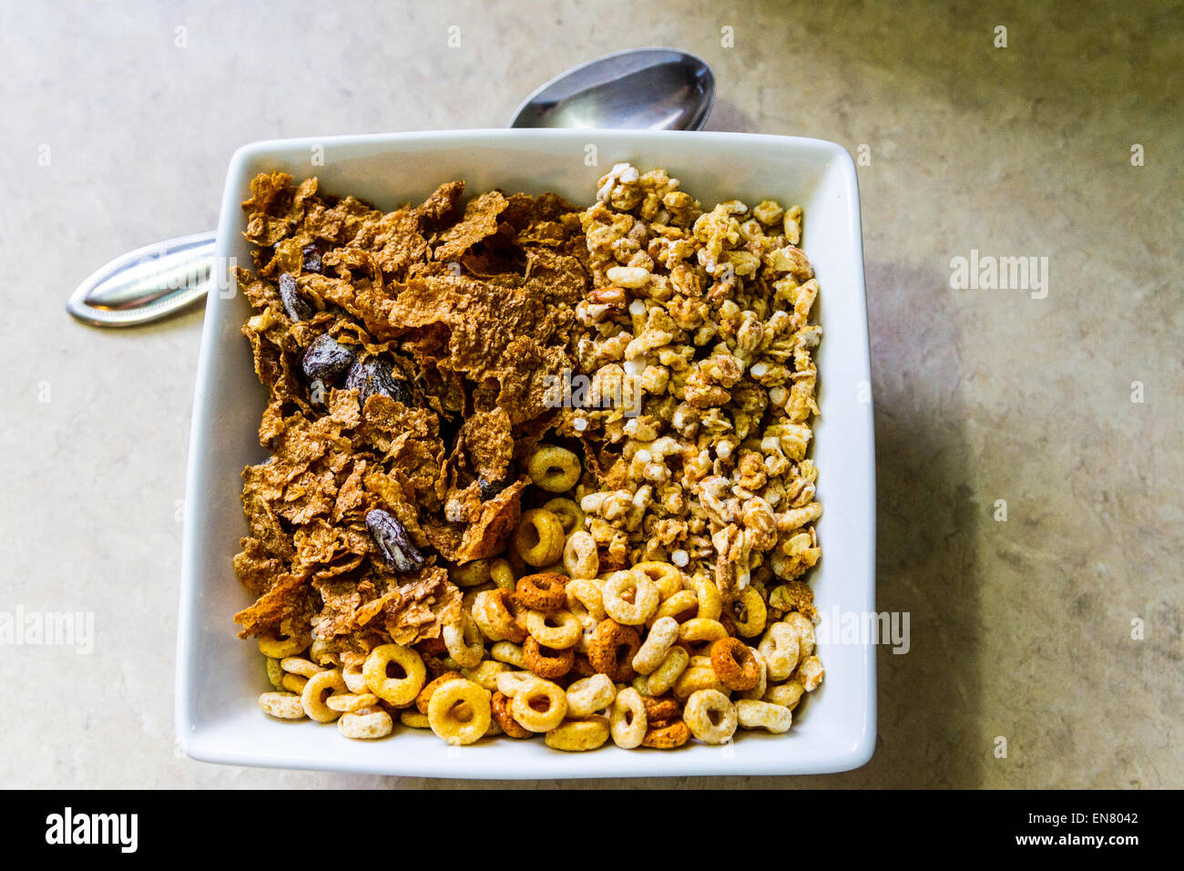 Cheerio's, Kashi Go Lean Crunch, and store brand raisin bran cereals in a square bowl for breakfast. Stock Photo