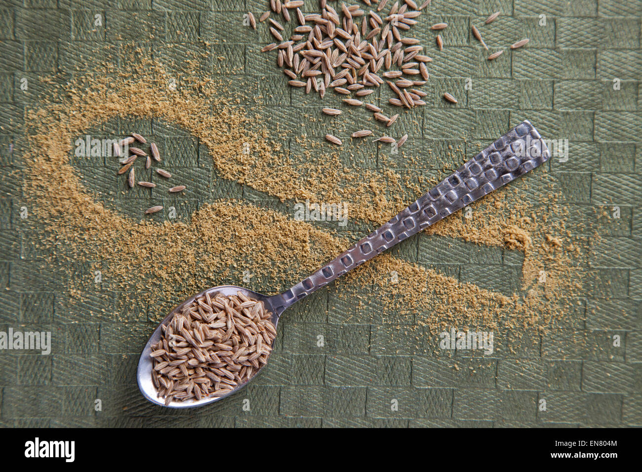 Shape of a spoon in randomly scattered cumin powder and cumin seeds on spoon Stock Photo