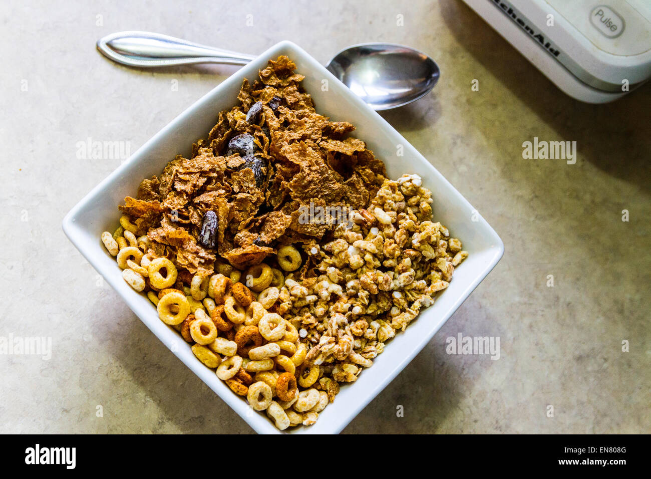 Cheerio's, Kashi Go Lean Crunch, and store brand raisin bran cereals in a square bowl for breakfast. Stock Photo