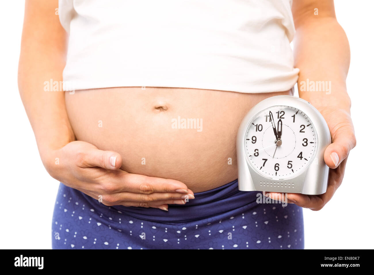 Pregnant woman showing clock and bump Stock Photo