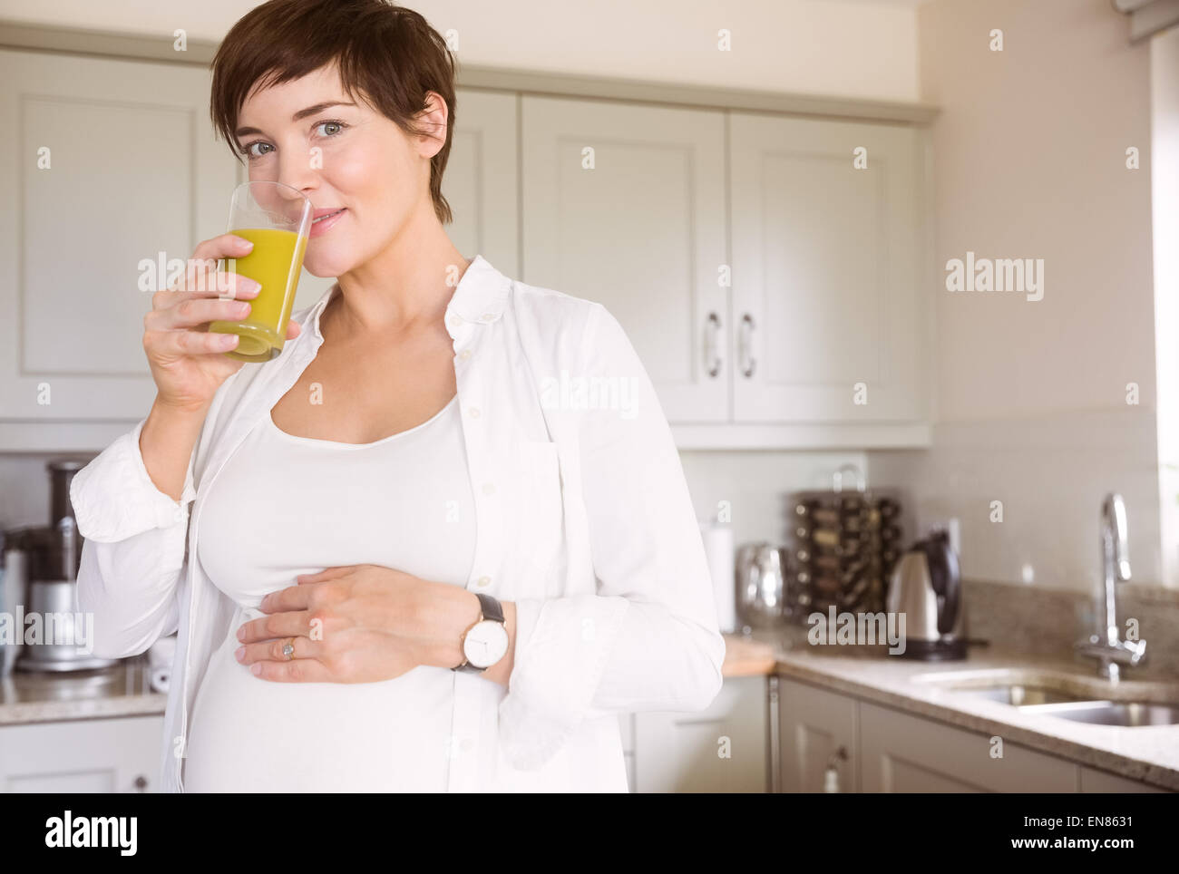 Pregnant woman drinking glass of orange juice Stock Photo - Alamy