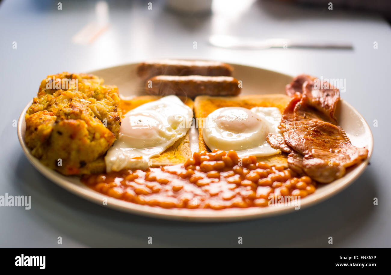 A picture of an English breakfast served up in a cafe in the UK. Sausages, eggs, beans, bacon, toast and bubble. Stock Photo