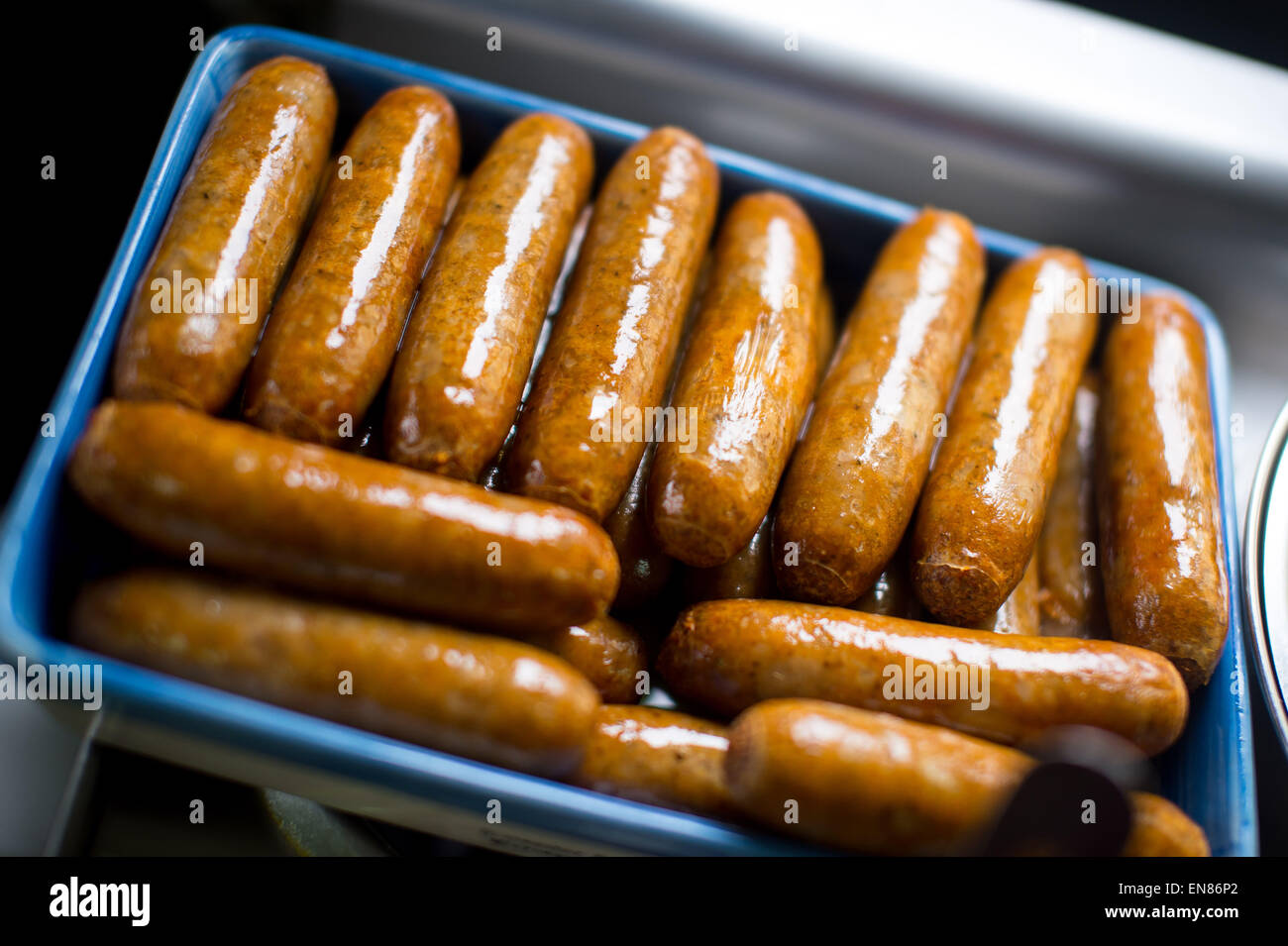 A batch of sausages sat in a baking tray after being cooked in an oven in a cafe in England, UK Stock Photo