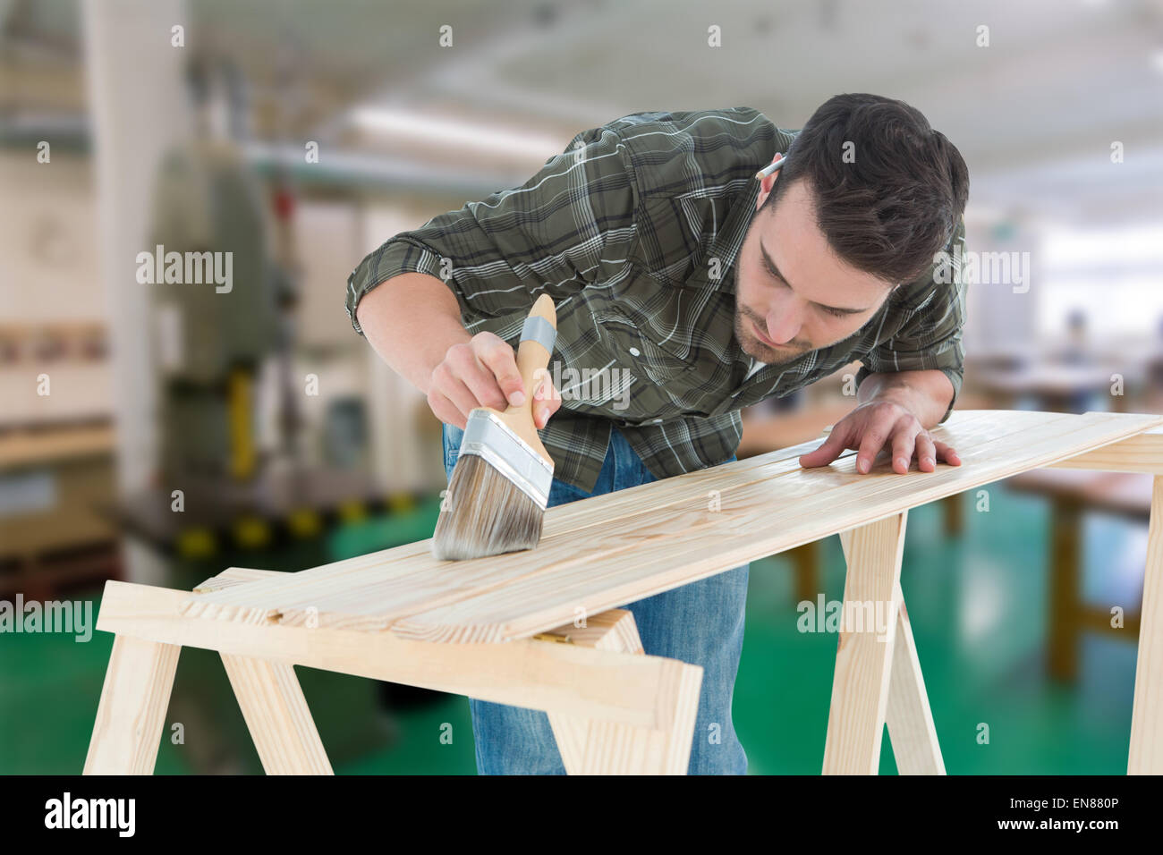Composite image of worker using brush on wooden plank Stock Photo