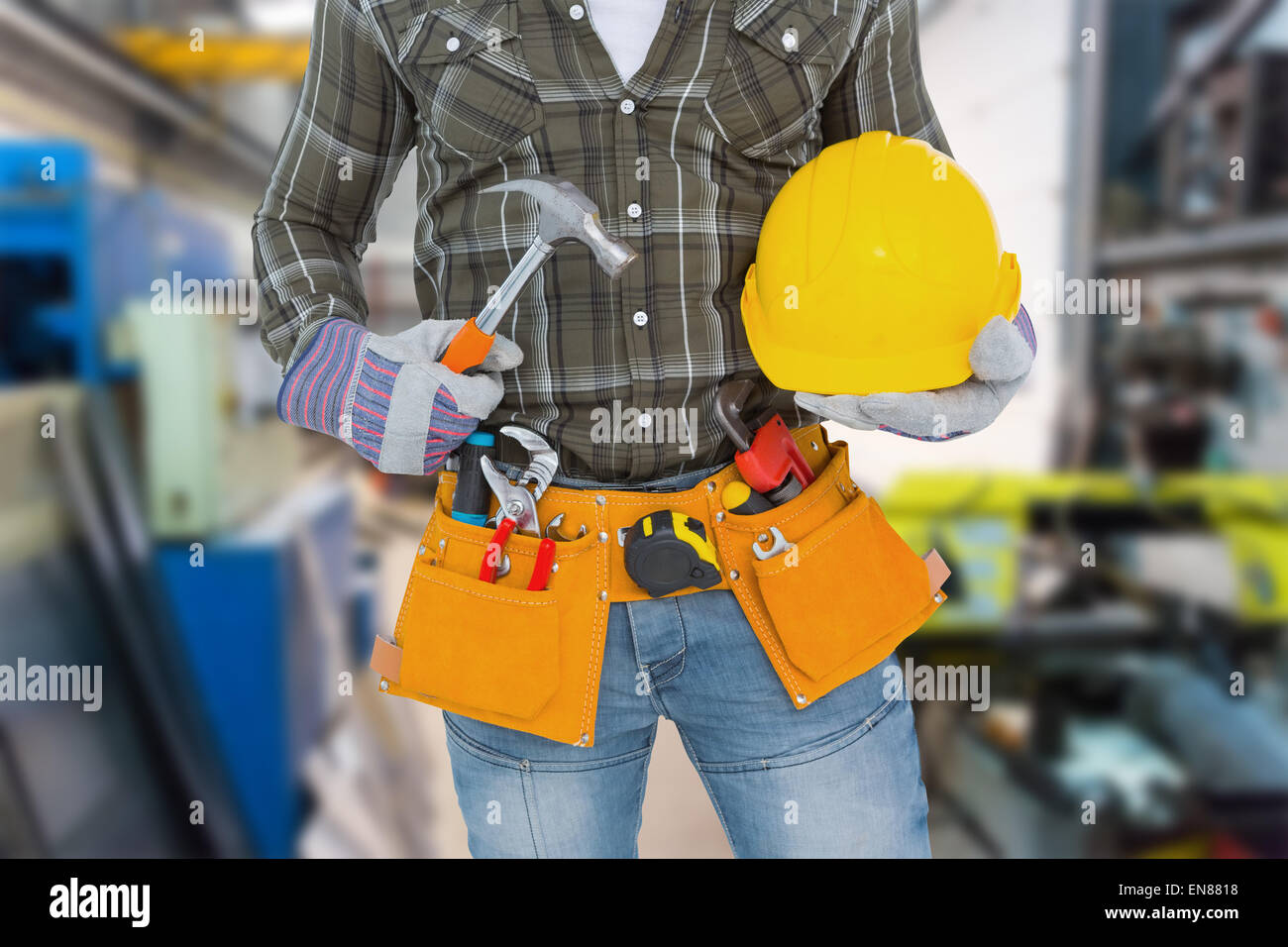 Composite image of manual worker wearing tool belt while holding hammer and helmet Stock Photo